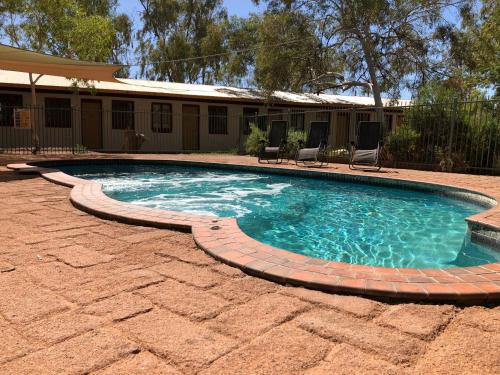 a swimming pool with a brick path around it at Discovery Resorts - Glen Helen in Glen Helen