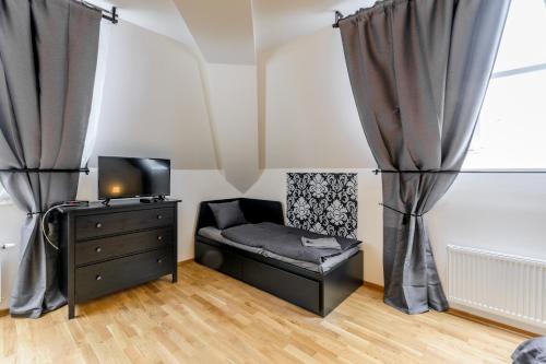 a room with a bed and a dresser and curtains at Riverside SPIRIT in Prague