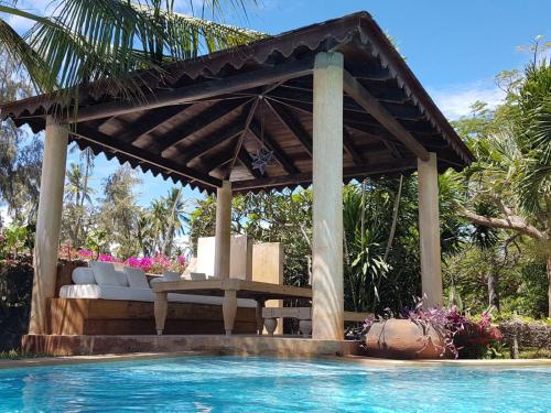 a wooden pergola next to a swimming pool at Villa Volandrella - in front of Watamu Beach in Watamu