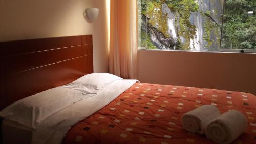 a bedroom with a bed with towels on it and a window at Casa Machu Picchu Hostel in Machu Picchu