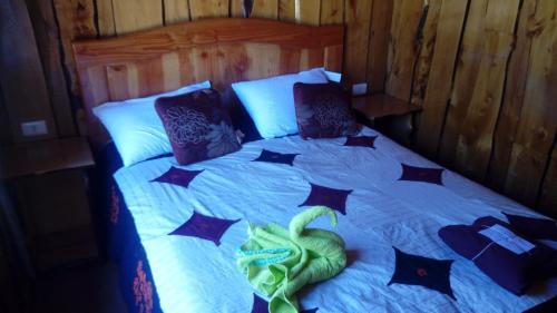 Una cama con almohadas negras y una serpiente verde. en Cabañas El Diuco en Coñaripe 2, en Coñaripe