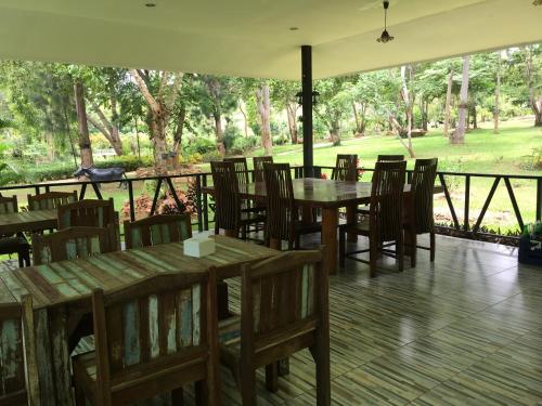 a restaurant with wooden tables and chairs on a deck at Baanraisooksangchan in Kaeng Krachan