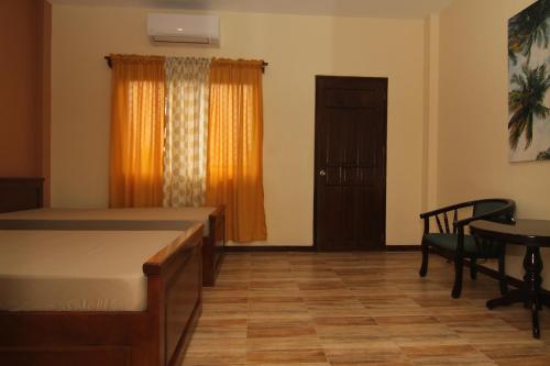 a bedroom with a bed and a table and a window at Charos Dormitel in Dumaguete