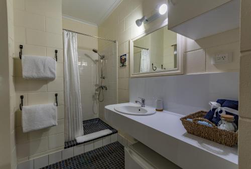 a white bathroom with a sink and a shower at Kookaburra Motel Yungaburra in Yungaburra