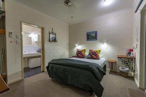 a small bedroom with a bed and a bathroom at Kookaburra Motel Yungaburra in Yungaburra