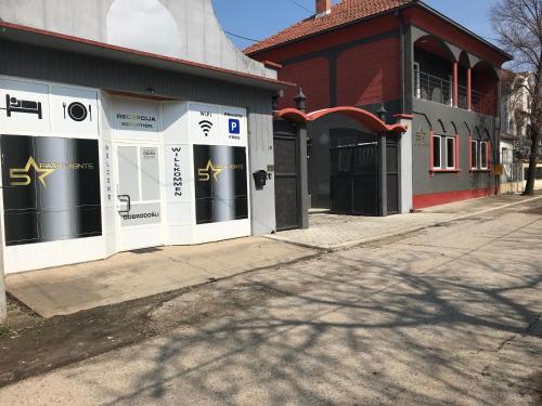 a building with windows on a street next to a sidewalk at Five Apartments in Inđija