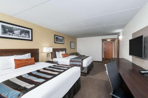 a hotel room with two beds and a desk at Wingate by Wyndham Bowling Green in Bowling Green