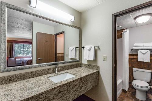 a bathroom with a sink and a toilet and a mirror at AmericInn by Wyndham Medora in Medora