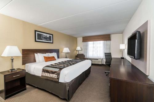 a hotel room with a bed and a flat screen tv at Wingate by Wyndham Bowling Green in Bowling Green