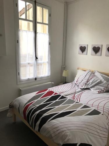 - une chambre avec un lit doté d'une couette à rayures et d'une fenêtre dans l'établissement Maison Bernadette - Rez-de-chaussée, à Vitry-sur-Seine
