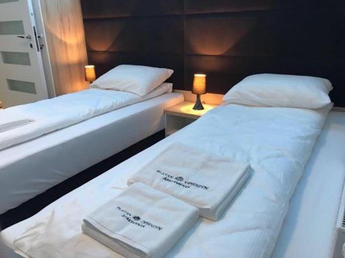 two beds in a hotel room with towels on them at Apartamenty Platan Opieszyn 2 in Września