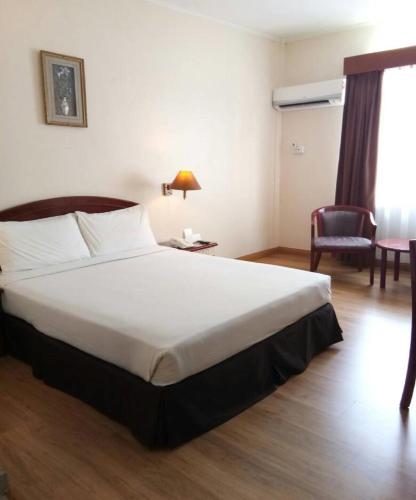 a hotel room with a large bed and a chair at Hotel Seri Malaysia Kuantan in Kuantan