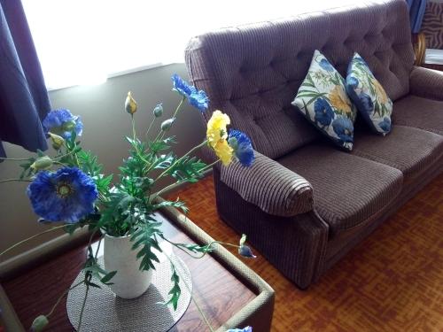 a living room with a couch and a vase with flowers at Redwood Lodge Motel in Levin