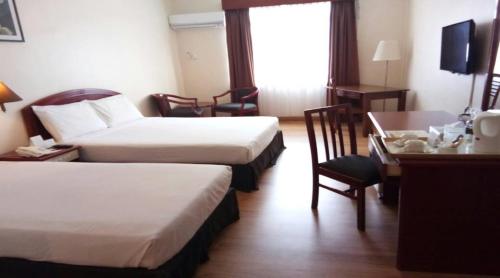 a hotel room with two beds and a desk at Hotel Seri Malaysia Kuantan in Kuantan