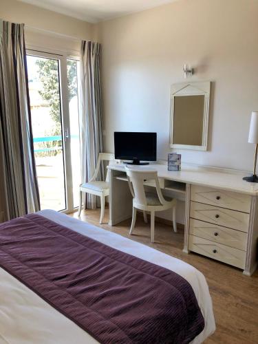 a bedroom with a bed and a desk with a computer at Hôtel Méditerranée in Le Lavandou