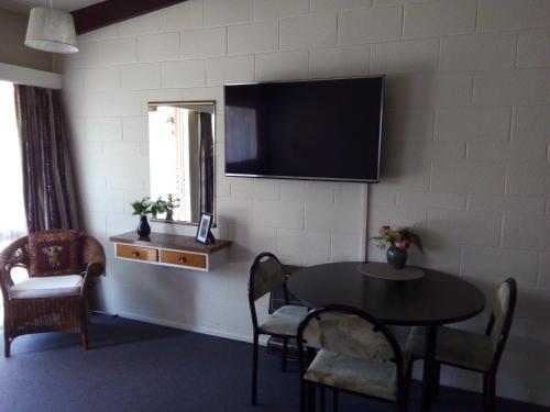 a room with a table and a television on a wall at Redwood Lodge Motel in Levin