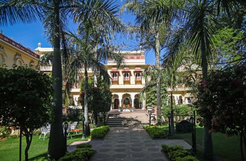 a large building with palm trees in front of it at Alsisar Haveli - Heritage Hotel in Jaipur
