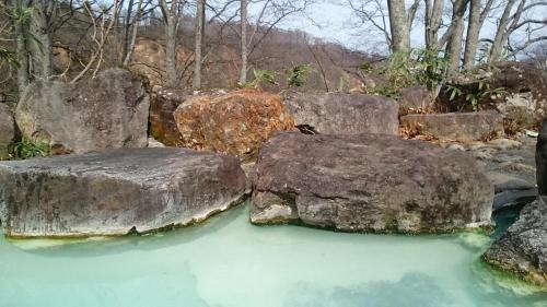 two large rocks sitting in a pool of water at Lodge Amenouo in Myoko
