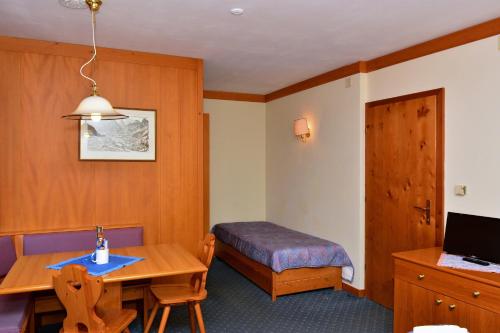 a room with a table and a bed and a room with a desk at Ski Residence in San Martino di Castrozza