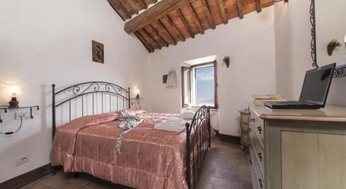 a bedroom with a bed and a desk with a laptop at Casa Bandino in Campiglia dʼOrcia