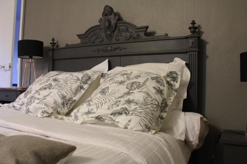 1 cama con cabecero de madera y almohadas en La chaumière du Tordoir, en Les Rues-des-Vignes