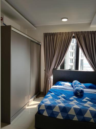 a bedroom with a blue and white bed with a window at Eclipse Residence Pangea in Cyberjaya