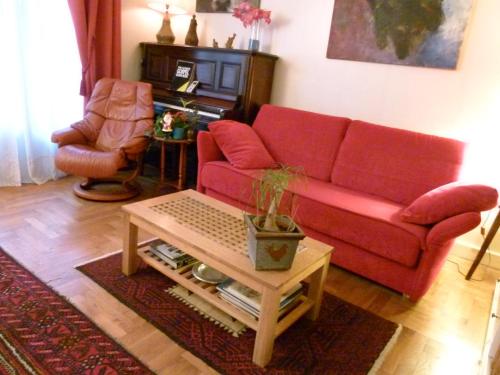 a living room with a red couch and a table at St Pothin Village avec garage in Lyon