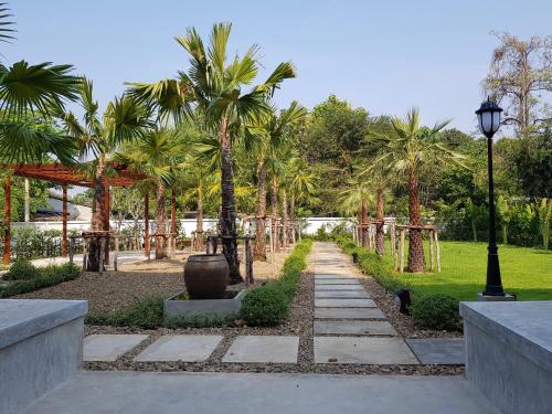 a path in a park with palm trees and a street light at Chez Bure - Bure Homestay in Kanchanaburi