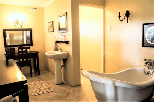 a bathroom with a white tub and a sink at Gerald's Gift Guest House in Addo