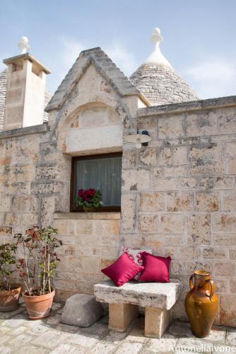 a stone building with two red pillows on a bench at Giardino Segreto in Putignano