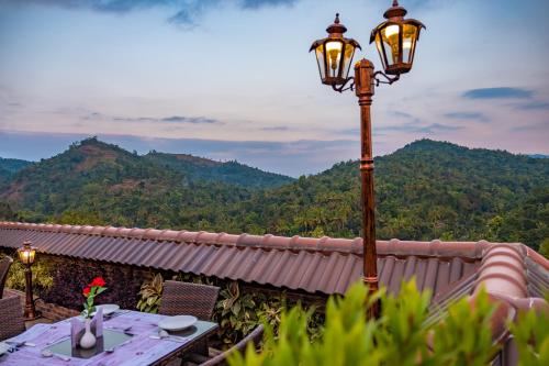 a street light on a patio with mountains in the background at Crown Valley Thekkady in Thekkady