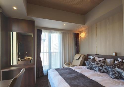 a hotel room with a large bed and a window at Hotel Coco Grand in Takasaki