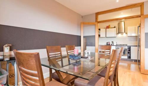uma sala de jantar com uma mesa de vidro e cadeiras em Dublin Corporate Apartment em Lucan