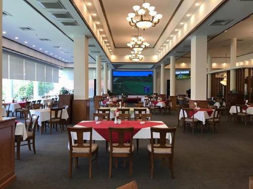 a dining room with tables and chairs and a television at Vietnam Golf - Lake View Villas in Ho Chi Minh City