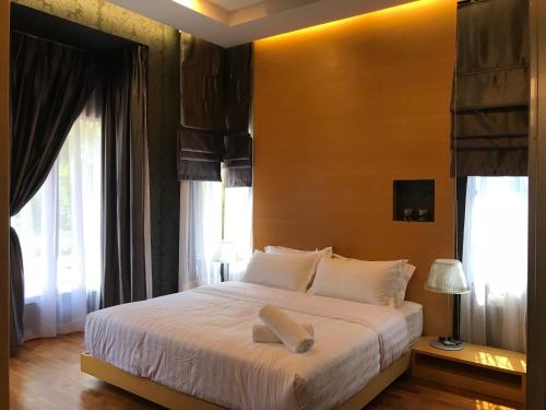 a bedroom with a large white bed with windows at Lakeside Home in Ipoh