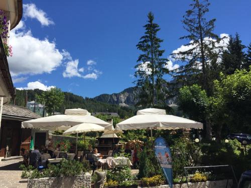 a restaurant with tables and umbrellas with mountains in the background at Boutique Hotel Villa Blu Cortina D'Ampezzo in Cortina dʼAmpezzo