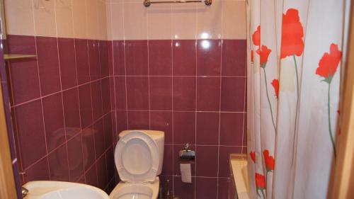 a bathroom with a toilet and a purple tiled wall at Hotel Sharmat in Pizunda