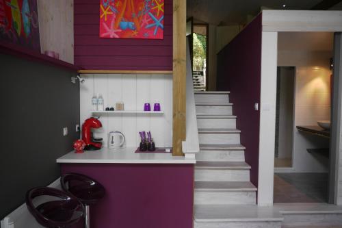 a kitchen with a purple wall and stairs at Un Matin D’été in Lacanau-Océan