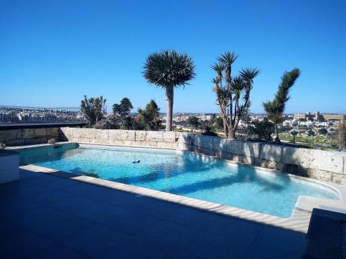 uma piscina com palmeiras ao fundo em St. Agatha's Bastion em Mdina