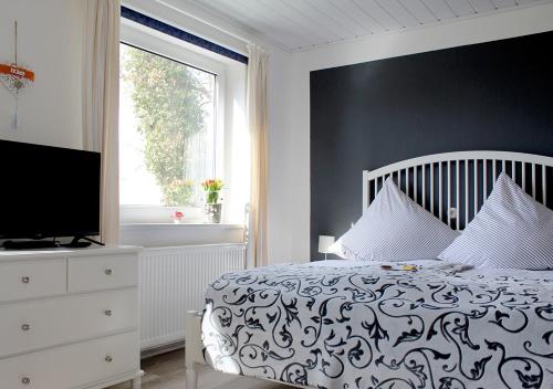1 dormitorio con 1 cama, TV y ventana en Ostseehaus Oe en Sierksdorf