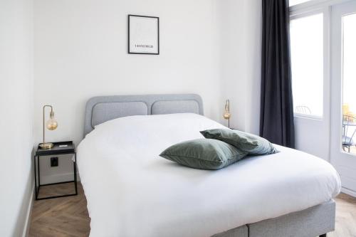 a white bed with a green pillow on it at Maison Bon Apartments in Den Bosch