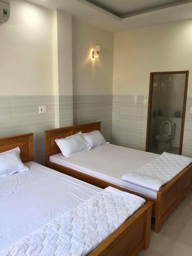 two twin beds in a room with a toilet at Nguyễn Kim Motel in Long Hai