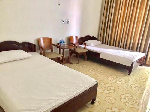 a room with two beds and a table and chairs at Nhà Khách T284 in Buon Ma Thuot