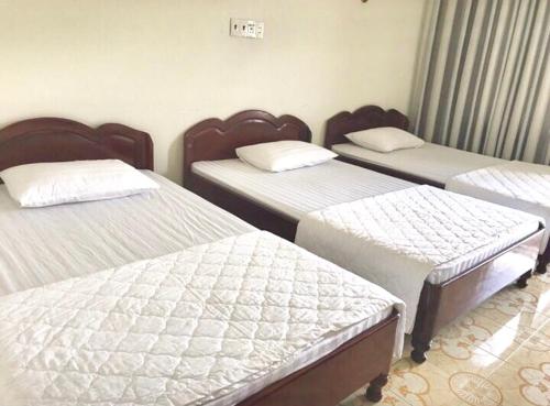 a room with three beds with white sheets at Nhà Khách T284 in Buon Ma Thuot