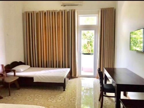 a bedroom with a bed and a desk and a window at Nhà Khách T284 in Buon Ma Thuot