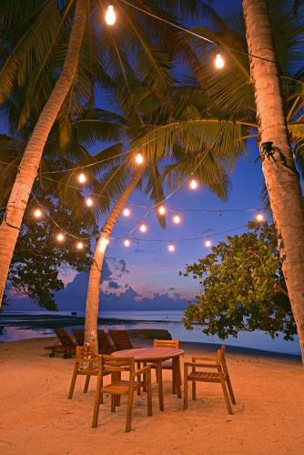 a table and chairs on a beach with palm trees at Veli Vilaa in Dhiffushi