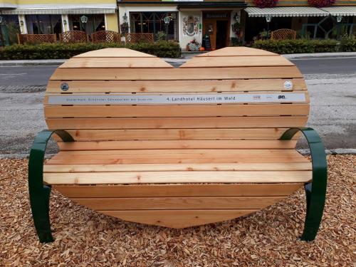 a wooden bench in the shape of a heart at Landhotel Häuserl im Wald in Gröbming