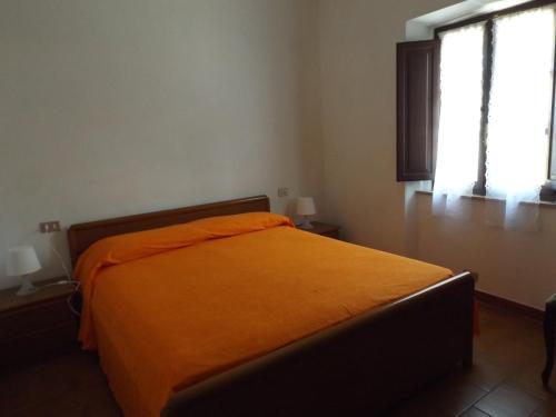 an orange bed in a room with two windows at Appartamento Il Girasole in Pomonte