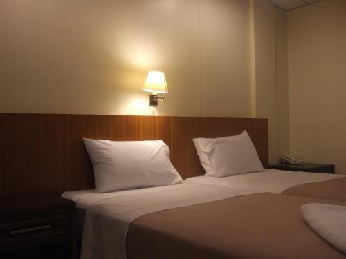 a bedroom with two beds with white pillows and a lamp at Lodge 61 Hotel in Bangkok