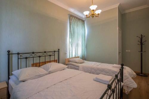 een slaapkamer met 2 bedden, een raam en een kroonluchter bij Gogi Dvalishvili Wine Cellar in Gori